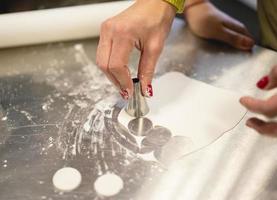 cook in the kitchen carves a circle of dough for cookies photo