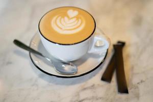 a fragrant and warm mug of cappuccino with a drawing heart, on table. photo