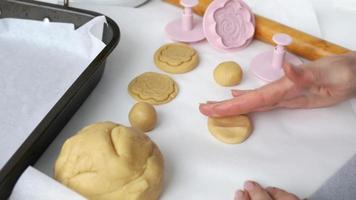 Process of making cookies with shapes press in the form of flowers, a rolling pin and tray, concept of cooking baking at home. Girls hands make biscuit from roll out dough and shaping it with pressing video