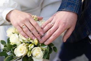 primer plano de los anillos de boda en las manos de la novia y el novio, una pareja enamorada tomándose de la mano. foto