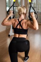 chica fuerte en el gimnasio bombeando sus brazos y músculos de la espalda en la máquina de ejercicios. foto