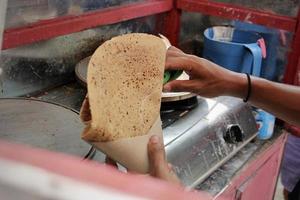 un joven vendedor está haciendo crepes de bocadillos en una calle cerca de un parque temático foto