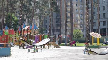 cerrar columpio de bebé vacío en el parque. Columpio de cadena nuevo. conjunto de cadenas de columpios negros en un parque infantil moderno. centrarse en el columpio en el fondo borroso. ucrania, kiev - 19 de agosto de 2021. video
