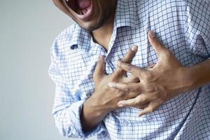 young man suffering pain in heart and holding chest with hand photo