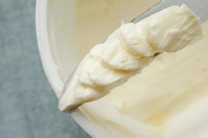 Mantequilla fresca en un recipiente con pan sobre fondo blanco. foto
