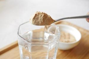 mixing brewers yeast flakes in a glass of water photo