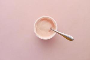 fresh yogurt in a plastic container and spoon on table photo