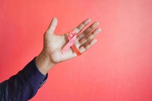 hand holding red HIV ribbon against red background photo