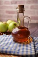 apple vinegar in glass bottle with fresh green apple on table photo