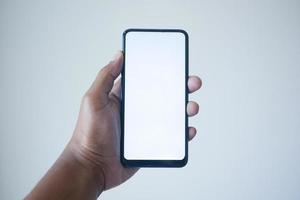 pov de la mano de un joven usando un teléfono inteligente con pantalla blanca foto