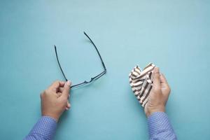 cleaning eyeglass with tissue close up photo