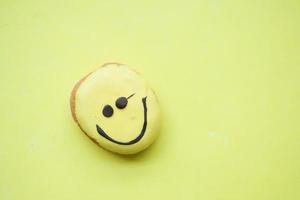 donuts de chocolate con cara sonriente sobre fondo amarillo foto