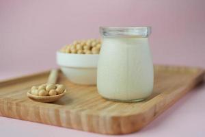 soy milk pouring in a glass jar on light pin background photo