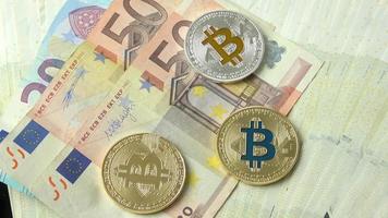 close-up de bitcoins em fundo de moeda euro. bitcoin dourado, bitcoin azul e bitcoin prata. video