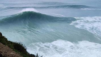 grandes vagues géantes se brisant à nazare, portugal dans l'océan. plus grosses vagues du monde. destination touristique pour le surf. océan agité. video
