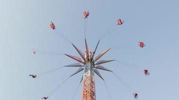 montez sur le grand carrousel du parc d'attractions. les gens s'amusent à se balancer sur une balançoire avec une chaîne haute, profitent de la balade contre le ciel bleu. ukraine, kharkiv - 17 juillet 2021. video
