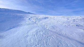 vue sur la montagne par une journée ensoleillée très venteuse. vent tourbillonnant la neige dans l'air. randonnée hivernale en plein air. voyage d'hiver. aventure et découverte des montagnes. video