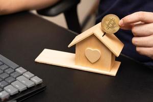 moneda bitcoin con modelo de casa de madera, concepto de propiedad comercial de dinero digital reemplaza la moneda principal. un enfoque selectivo. foto