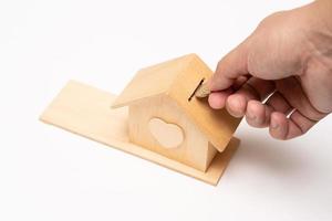 Property investment and house mortgage financial concept, Hand putting money coin stack with wooden house. selective focus. isolated on white background. photo