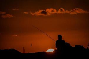 pescador sobre la puesta de sol foto
