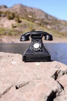 Black telephone on a rock photo