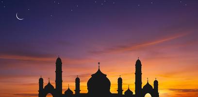 Panoramic view of silhouette mosque dome against colorful dusk sky and crescent moon with stars in the evening twilight, background design for iftar period during Ramadan Holy month photo