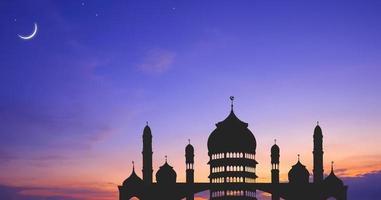 silueta de la cúpula de la mezquita contra el colorido cielo del atardecer y la luna creciente con estrellas en el crepúsculo vespertino, diseño de fondo para el período iftar durante el mes sagrado del ramadán foto