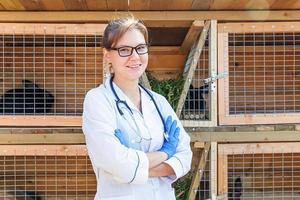 Veterinarian woman with stethoscope on barn ranch background. Vet doctor check up rabbit in natural eco farm. Animal care and ecological livestock farming concept. photo