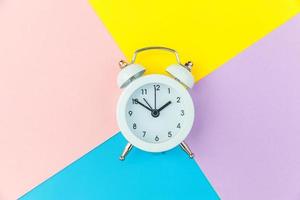 Ringing twin bell classic alarm clock isolated on blue yellow pink pastel colorful geometric background. Rest hours time of life good morning night wake up awake concept. Flat lay top view copy space. photo