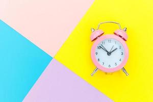 Ringing twin bell classic alarm clock isolated on blue yellow pink pastel colorful geometric background. Rest hours time of life good morning night wake up awake concept. Flat lay top view copy space. photo