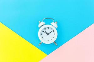 Ringing twin bell classic alarm clock isolated on blue yellow pink pastel colorful geometric background. Rest hours time of life good morning night wake up awake concept. Flat lay top view copy space. photo