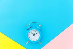 Ringing twin bell classic alarm clock isolated on blue yellow pink pastel colorful geometric background. Rest hours time of life good morning night wake up awake concept. Flat lay top view copy space. photo
