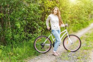 mujer joven montando en bicicleta en el parque de la ciudad de verano al aire libre. gente activa chica hipster relajarse y andar en bicicleta foto