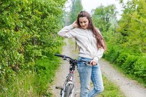 mujer joven montando en bicicleta en el parque de la ciudad de verano al aire libre. gente activa chica hipster relajarse y andar en bicicleta foto