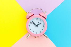 Ringing twin bell classic alarm clock isolated on blue yellow pink pastel colorful geometric background. Rest hours time of life good morning night wake up awake concept. Flat lay top view copy space. photo