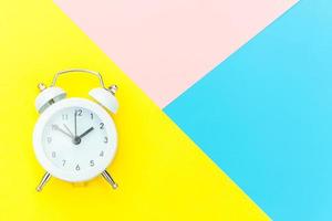 Ringing twin bell classic alarm clock isolated on blue yellow pink pastel colorful geometric background. Rest hours time of life good morning night wake up awake concept. Flat lay top view copy space. photo