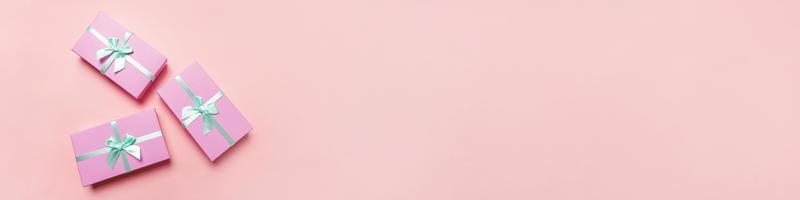 navidad año nuevo cumpleaños san valentín celebración presente concepto romántico. simplemente diseño minimalista tres cajas de regalo rosa aisladas sobre fondo de color rosa pastel. espacio de copia de vista superior plana, banner foto