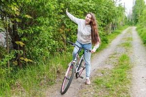 Young woman riding bicycle in summer city park outdoors. Active people. Hipster girl relax and rider bike photo