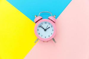 Ringing twin bell classic alarm clock isolated on blue yellow pink pastel colorful geometric background. Rest hours time of life good morning night wake up awake concept. Flat lay top view copy space. photo