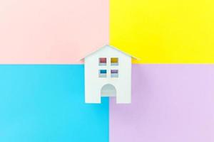 Simply design miniature white toy house isolated on blue yellow pink purple pastel colorful trendy geometric background Mortgage property insurance dream home concept. Flat lay top view copy space. photo
