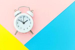 Ringing twin bell classic alarm clock isolated on blue yellow pink pastel colorful geometric background. Rest hours time of life good morning night wake up awake concept. Flat lay top view copy space. photo