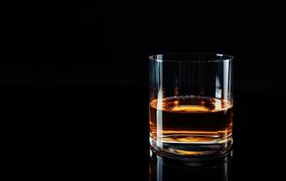 elegante y sencillo vaso de whisky de lujo con fondo negro. fondo aislado de vidrio de whisky brillante, foto de estudio. espacio de copia. bebida alcohólica fuerte.