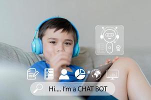 Technology Education concept,School kid holding tablet and wearing headphones tacking or listening to a chatbot for homework,Boy using system AI Chatbot on Mobile application for research on internet photo