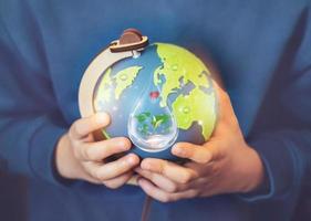 Hand  holding green world globe with tree growing on water, environment icon in rain drop, Save world, sustainable Reduce CO2 emission,Earth day on April 22,Green World environment day concept photo