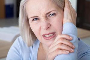 Tinnitus. Closeup up side profile sick female having ear pain touching her painful head. photo