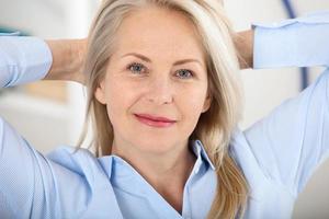 Modern businesswoman. Beautiful middle aged woman looking at camera with smile while siting in the office. photo