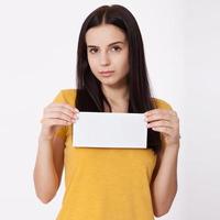 Your text here. Pretty young woman holding empty blank board. Studio portrait on white background. Mock up for design photo