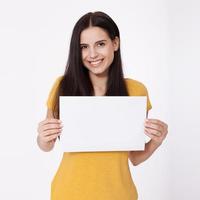 Your text here. Pretty young woman holding empty blank board. Studio portrait on white background. Mock up for design photo