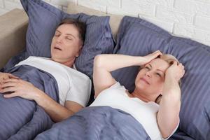 hombre roncando pareja en la cama, hombre roncando y mujer no puede dormir. pareja de mediana edad en la cama en casa. foto