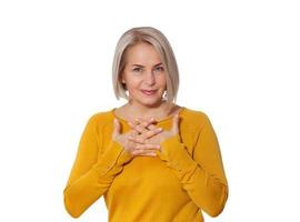 Middle aged blonde emotionally posing in a studio. Happy woman in yellow bright sweater on white background photo